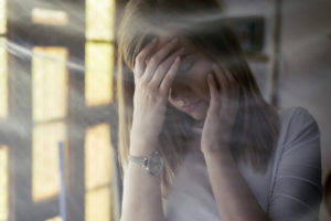 beautiful sad lonely girl sitting near the window during the day suffering from headache at home