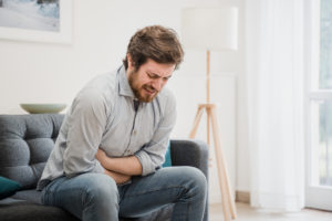 Guy feeling unwell with a heartburn while sitting at home