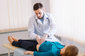 The doctor examines a female patient on the table.