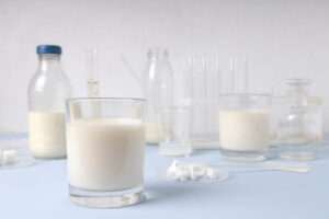 Closeup of glass of milk sign and test Lactose Free, lab glassware on the blue sirface against white wal