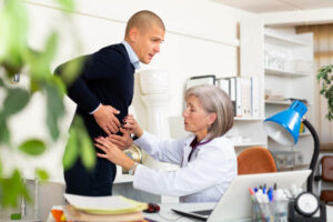 European man complaining about stomach ache to elderly woman physician. She's palpating pain localisation.