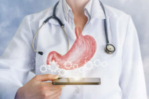 A digital stomach model inside the cogwheel scheme ia hanging above a device in the doctor's hand. The concept is the role of technology in the internal organs diagnosis